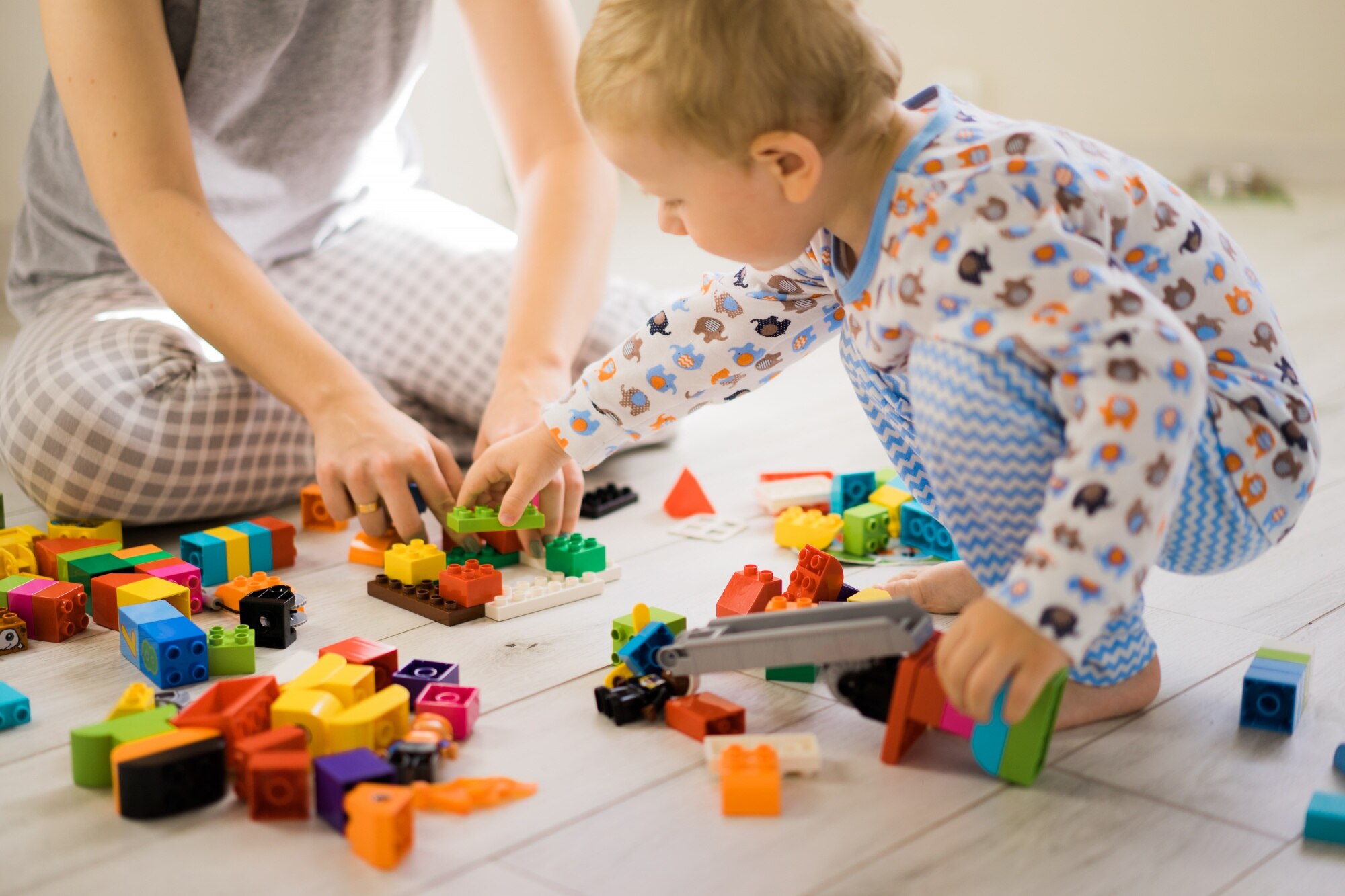 Jeune enfant jouant avec des blocs de construction colorés sous la supervision d'un adulte, illustrant l'évaluation psychomotrice avec l'échelle de développement Brunet-Lézine (BLR), réalisée par Florence Ronco, neuropsychologue à Paris 5.