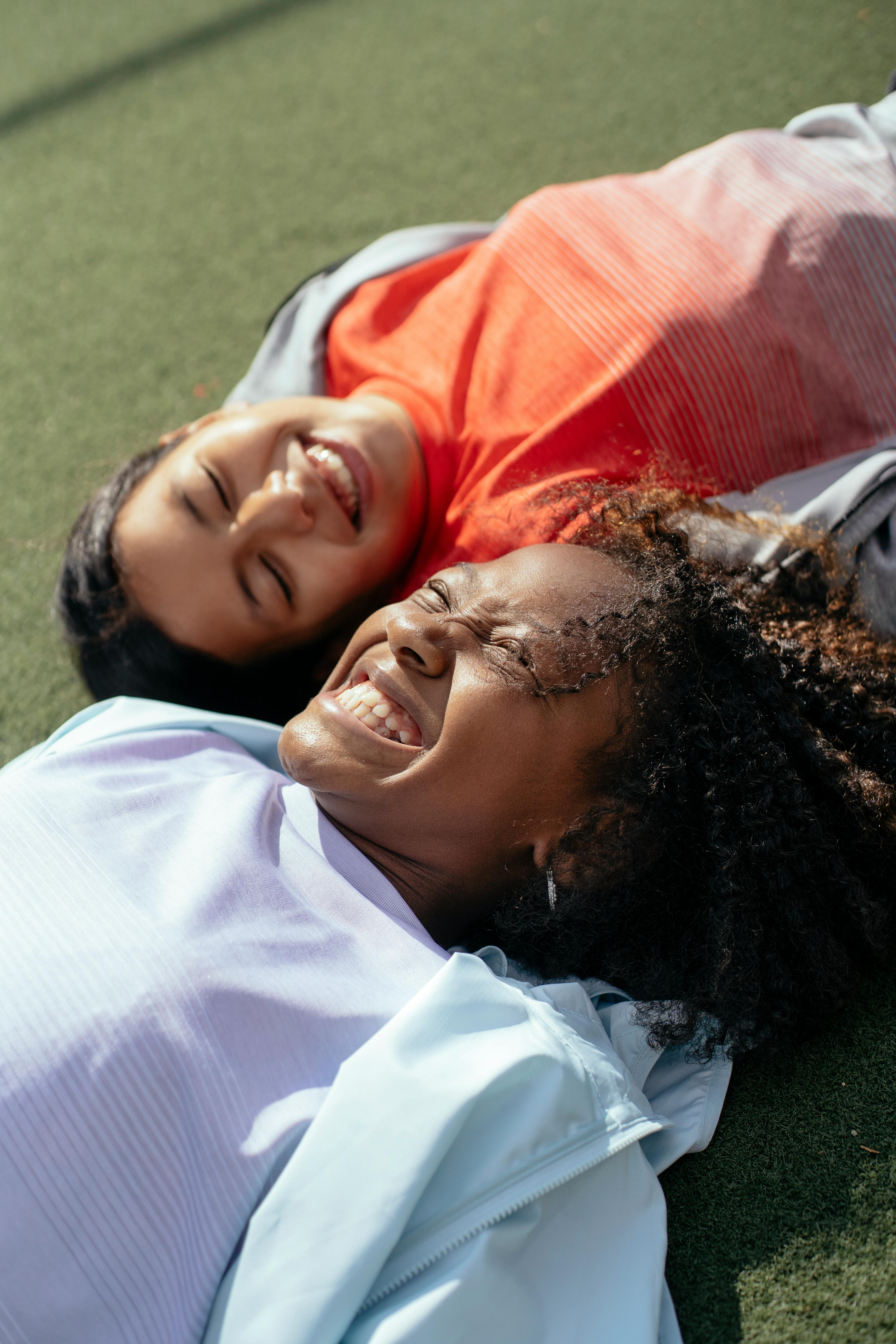 Deux adolescentes souriantes allongées sur le sol, illustrant un bilan neuropsychologique avec le MMPI-A (Inventaire multiphasique de personnalité du Minnesota pour adolescents de 14 à 18 ans, 1998) réalisé par Florence Ronco, neuropsychologue à Paris 5.