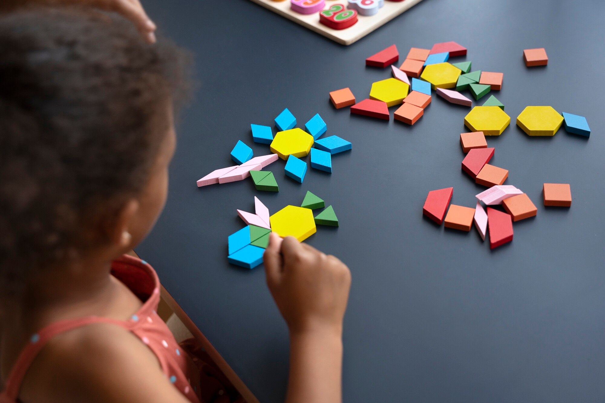 Enfant réalisant un puzzle géométrique coloré, illustrant un bilan neuropsychologique avec le test de la Figure Complexe de Rey (1960), réalisé par Florence Ronco, neuropsychologue à Paris 5.