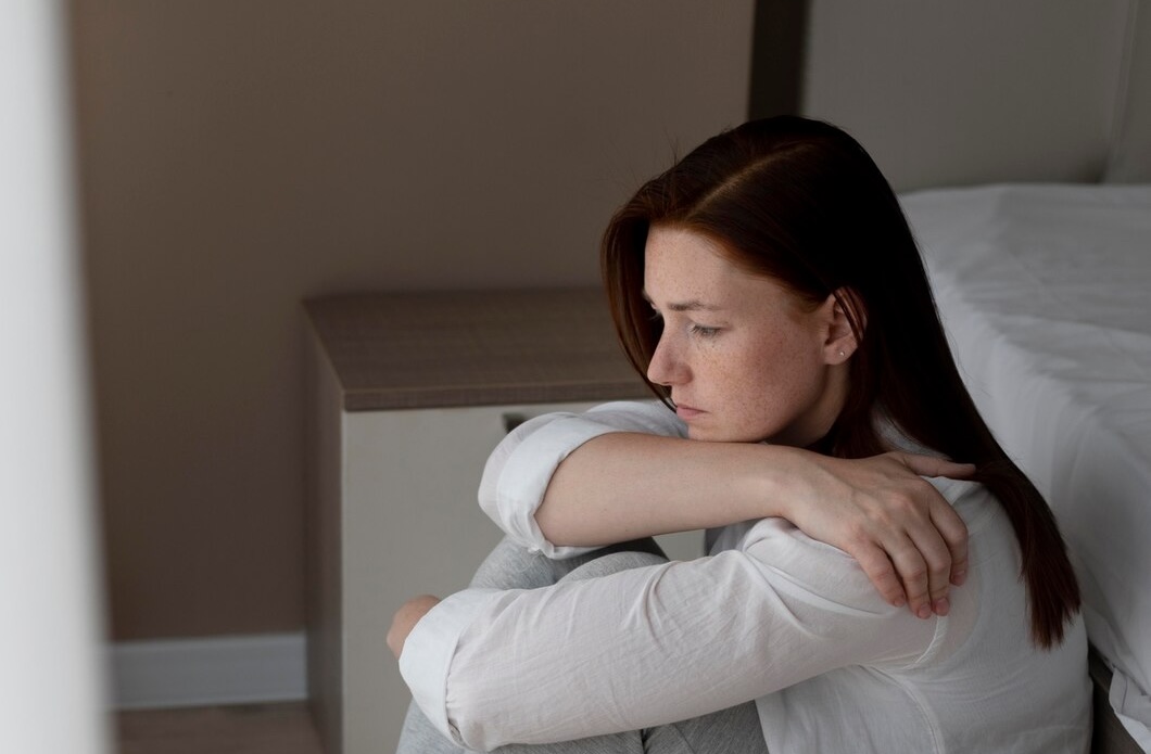 Femme assise au sol dans une posture introspective, illustrant un bilan neuropsychologique avec le SCL-90-R (Inventaire de symptômes psychologiques en auto-questionnaire, 2015) réalisé par Florence Ronco, neuropsychologue à Paris 5.