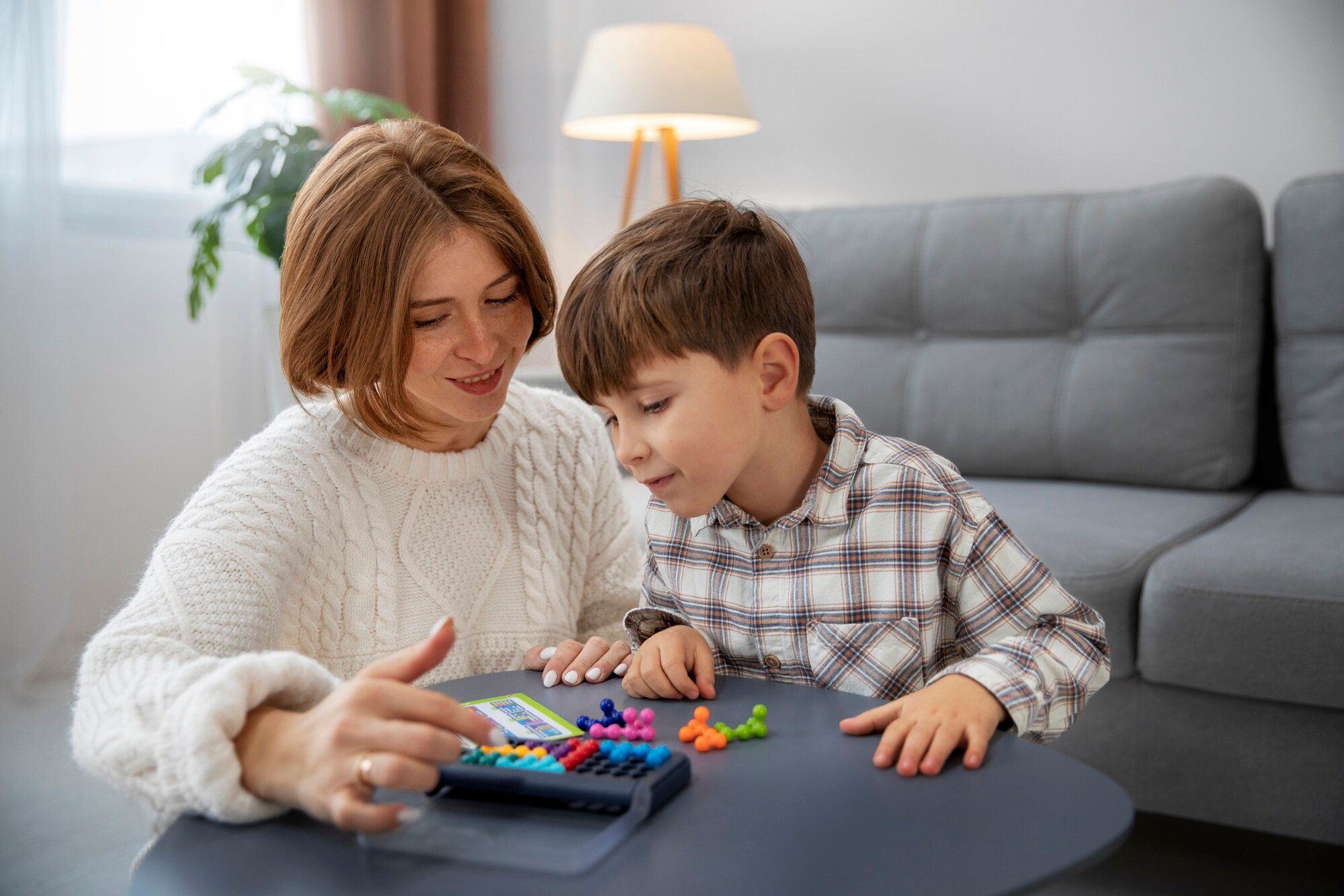 Une mère jouant avec son enfant à l’aide d’un jeu coloré, illustrant un bilan neuropsychologique avec le TEA-Ch (Test d’évaluation de l’attention chez l’enfant, 2004) réalisé par Florence Ronco, neuropsychologue à Paris 5.